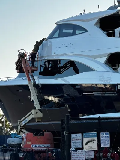 Detailer on a lift working the hull of a superyacht
