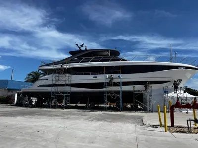 Superyacht under scaffolding with a crew working the hull